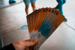 A hand holds brown and blue tickets for the Space Needle.