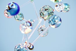 An abstract computer rendering of glassy orbs connected by thin, transparent strands in front of a light blue background.