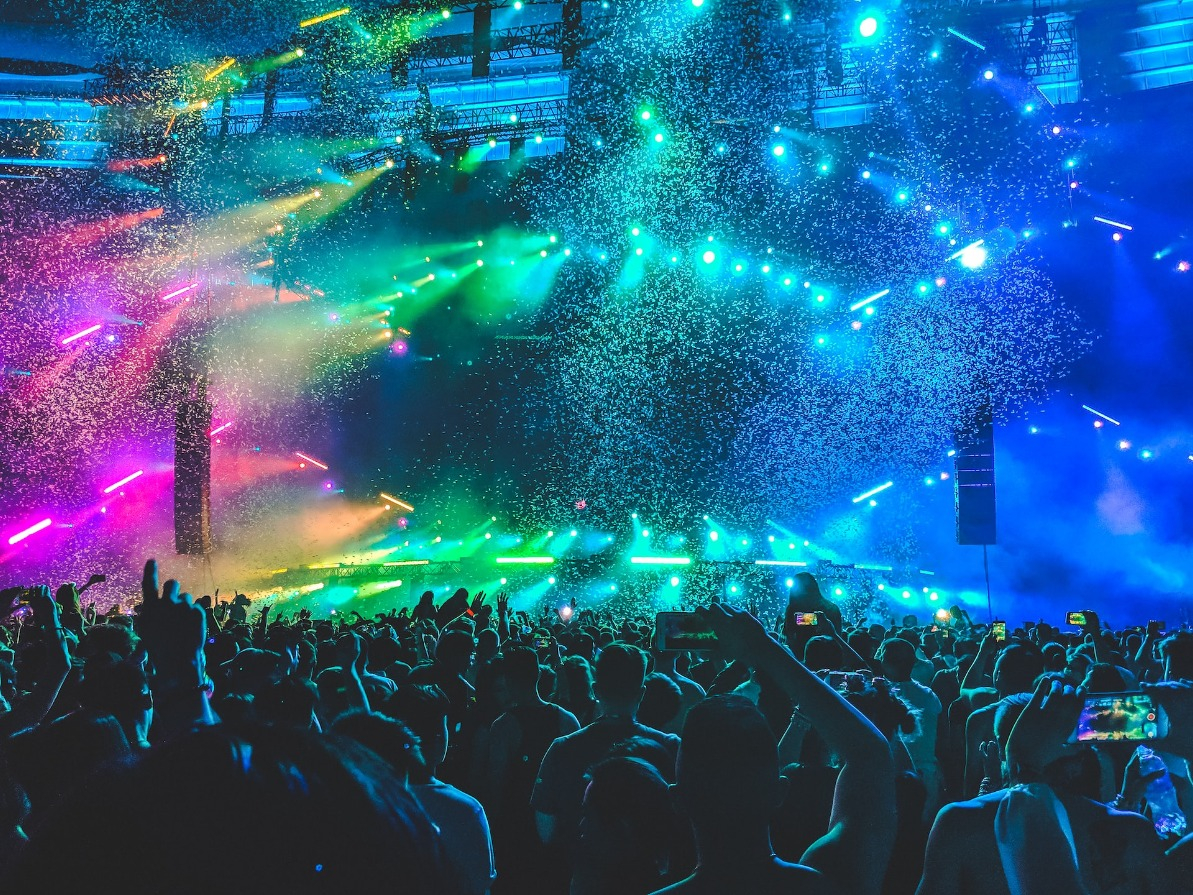 Colors and lights pop at a concert from the perspective of an audience member looking toward the stage.