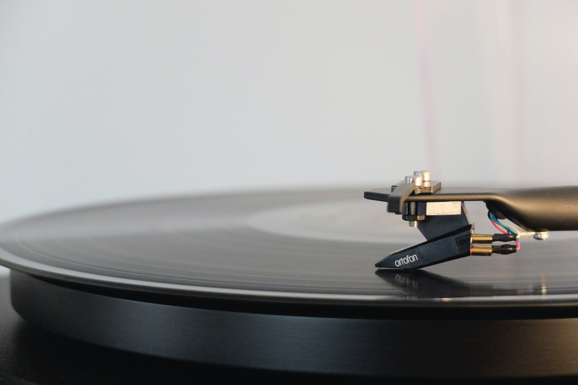 A closeup, side-on view of a monochromatic record turntable in action.