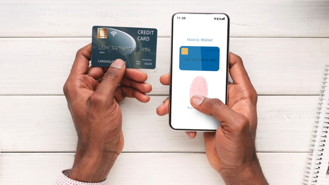 A bird's eye view of a set of hands, with one hand holding a credit card and the other hand holding a mobile phone with the screen showing the credit card's mobile wallet app.