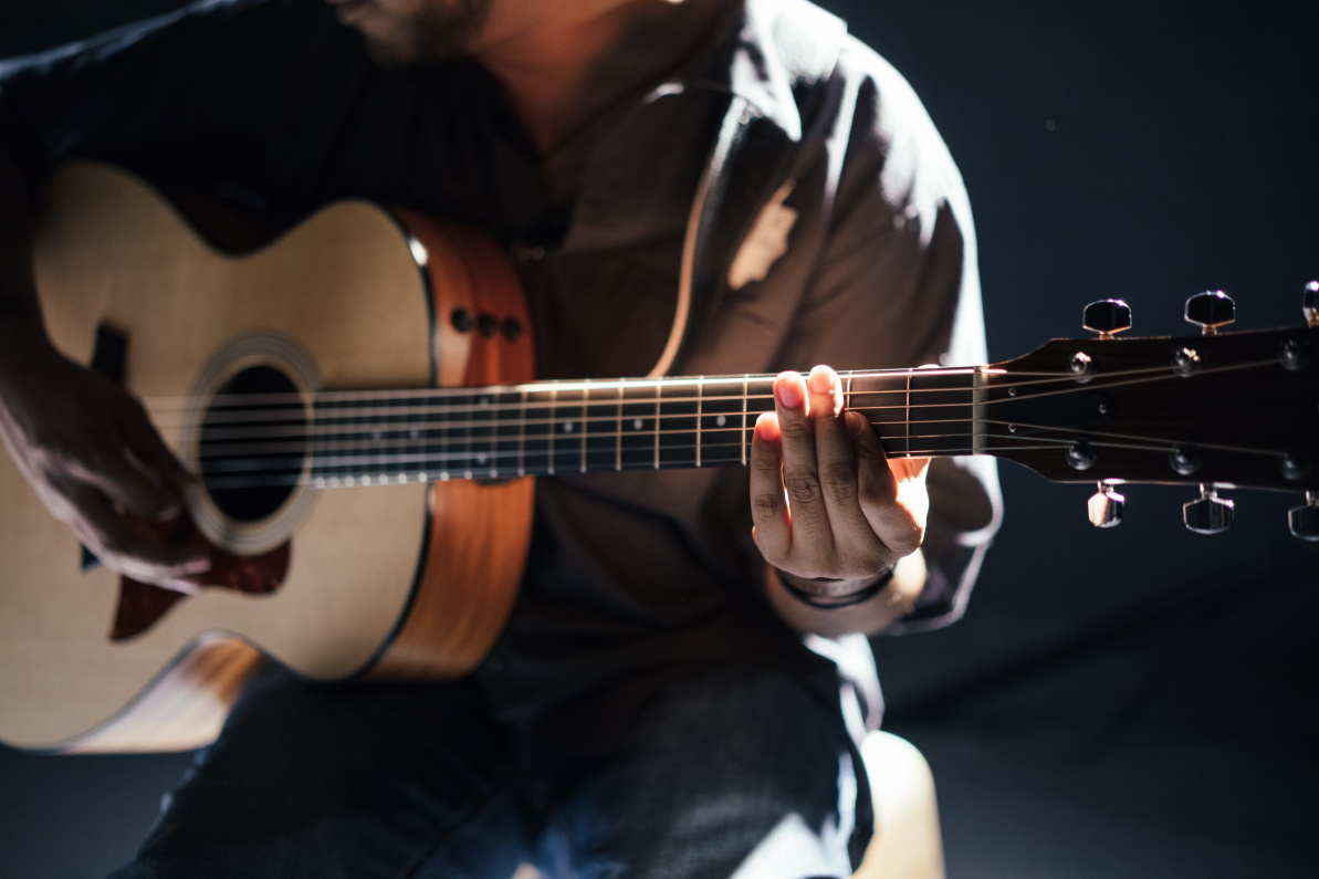 Acoustic guitar player in pale light.
