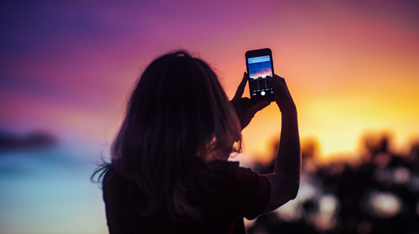  Woman using her phone to take picture of a sunrise 