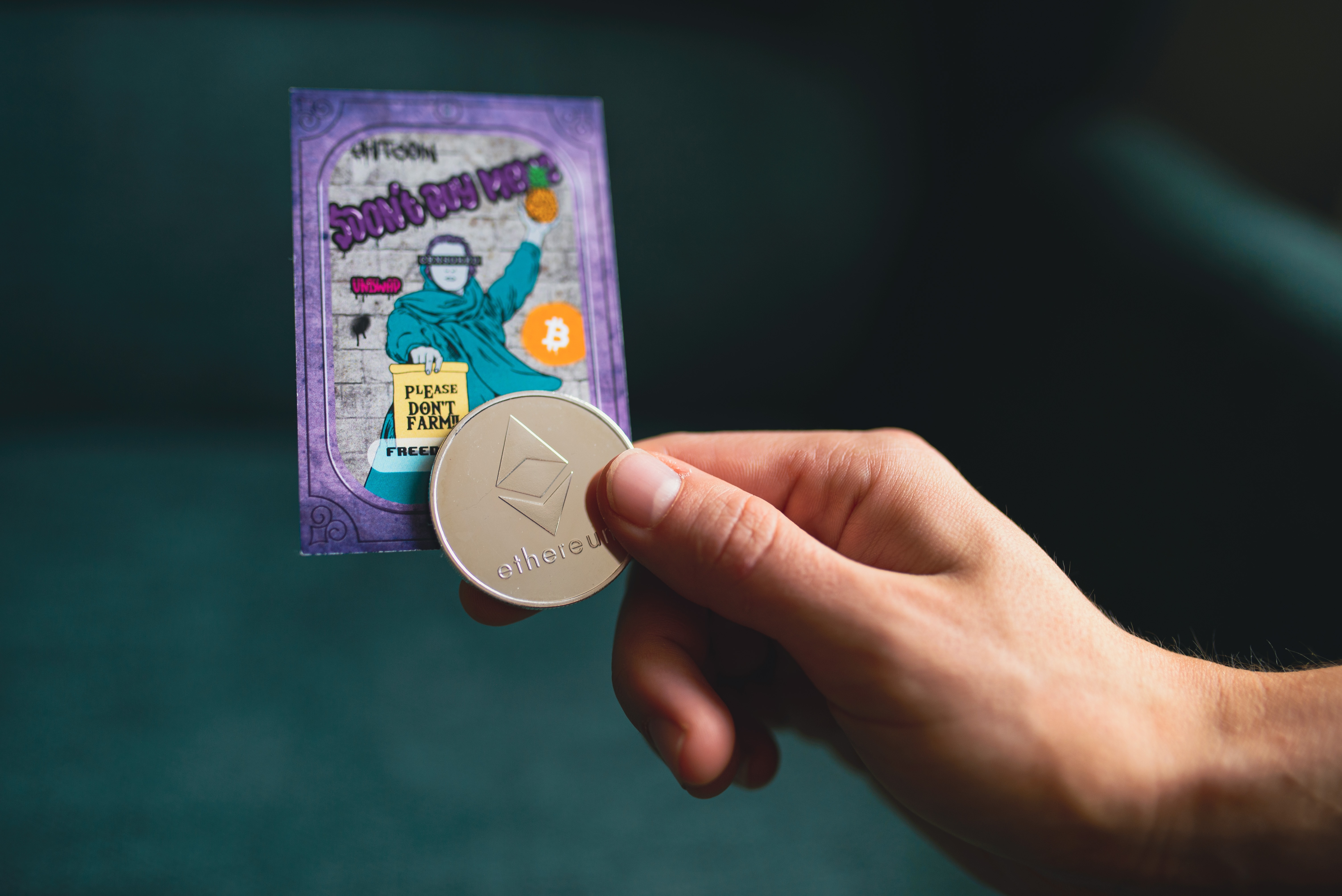 A hand holding a metal ether coin and a collectible card, representing asset tokenization in action.