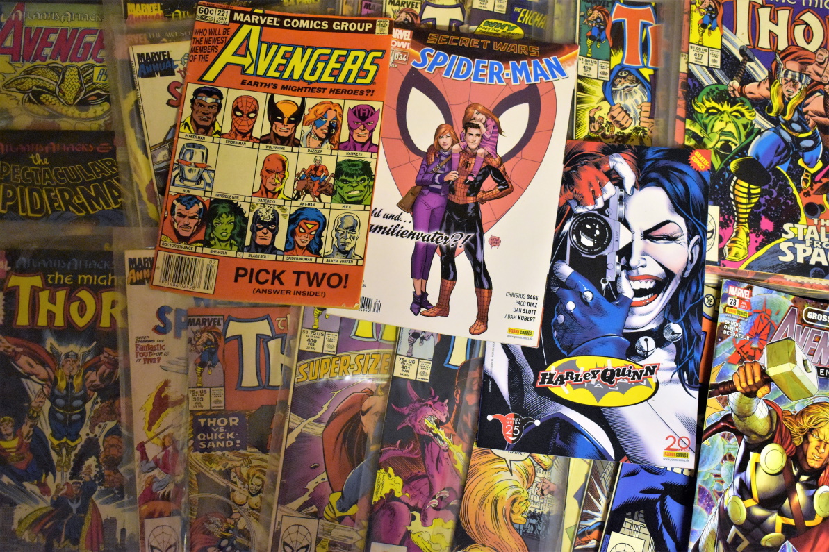 Collectible comic books spread across a table with protective plastic sleeves.